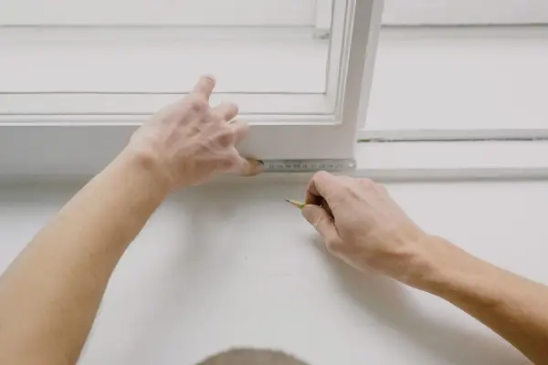 Medición con metro y lápiz sobre el marco blanco de una ventana, como en una visita de persianista en Pamplona Medición con metro y lápiz sobre el marco blanco de una ventana, como en una visita de persianista en Pamplona