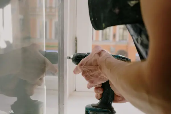 Manos de un operario atornillando una ventana con un taladro, igual que en una reparación a domicilio en Pamplona Manos de un operario atornillando una ventana con un taladro, igual que en una reparación a domicilio en Pamplona